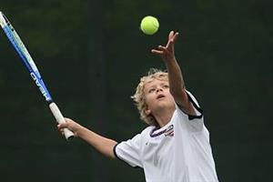 Young Boy Serving Tennis Ball
